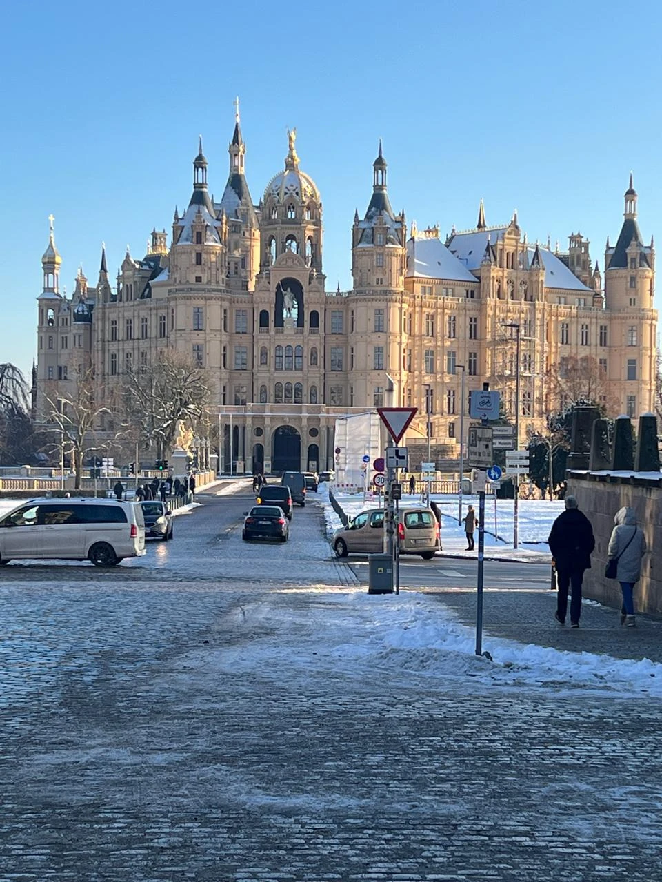 Schweriner Schloss hinter einer verschneiten Straße unter blauem Himmel