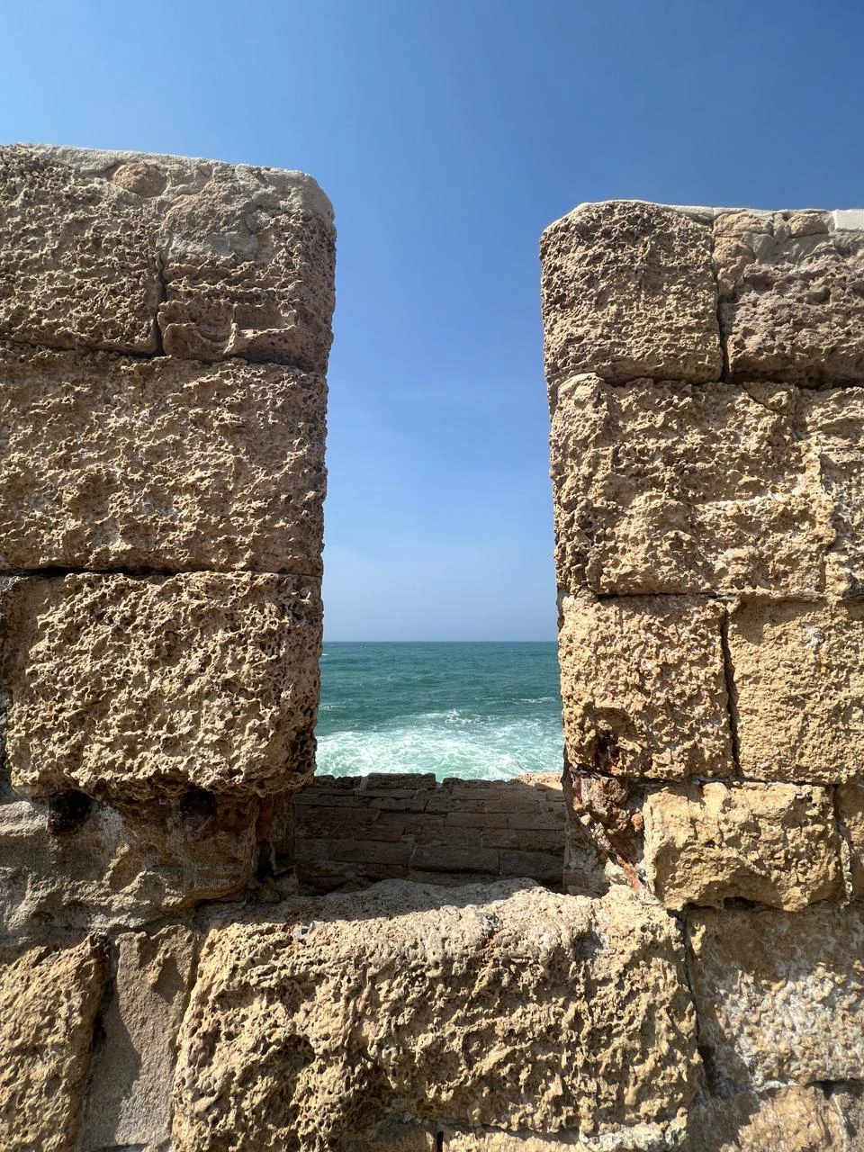 Blick zwischen hohen Steinmauern auf das Meer